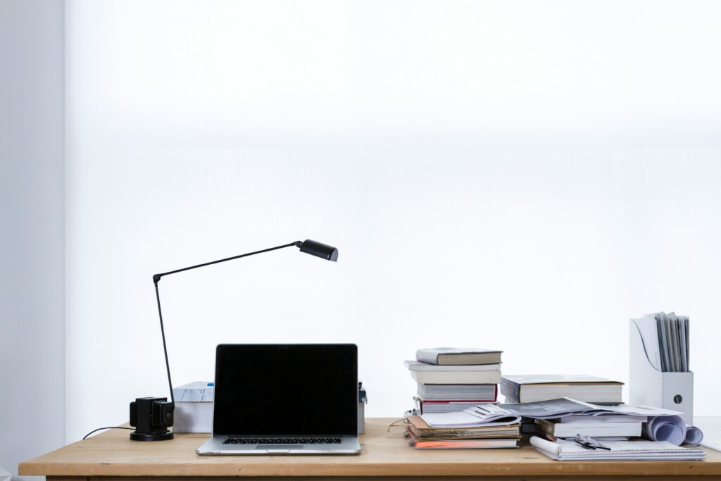 Picture of a desk with a MacBook Pro laptop and some books and papers